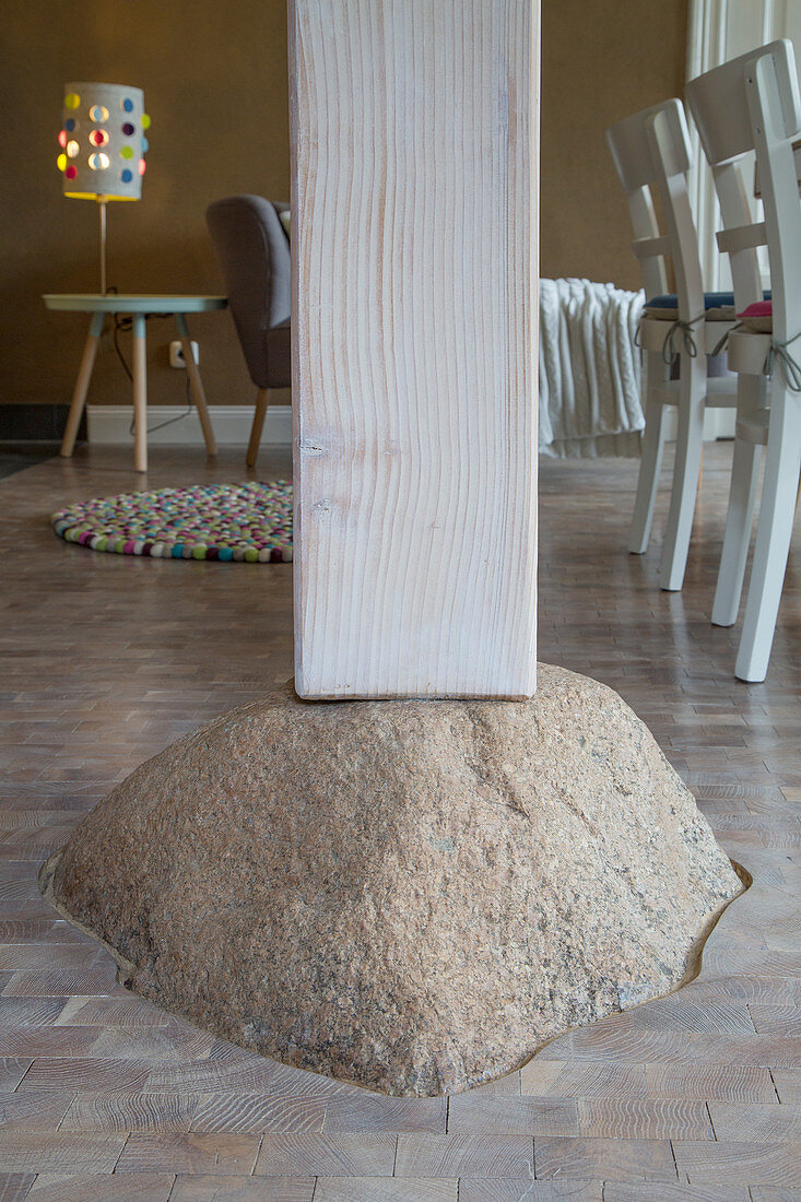 Wooden pillar supported on boulder in open-plan interior