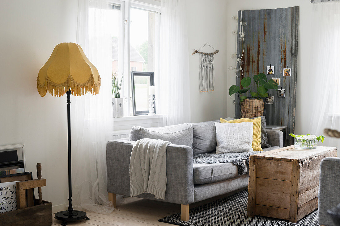 Grey sofa and wooden crate used as coffee table in rustic living room