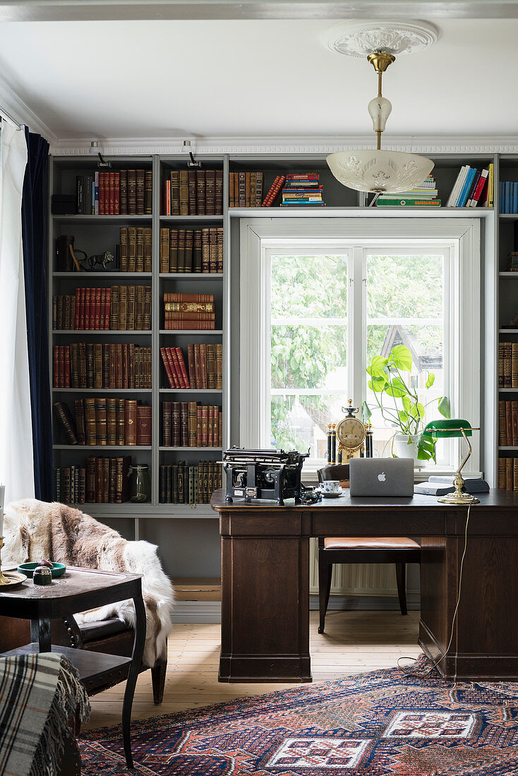 Dark desk in front of old books in bookcase in study