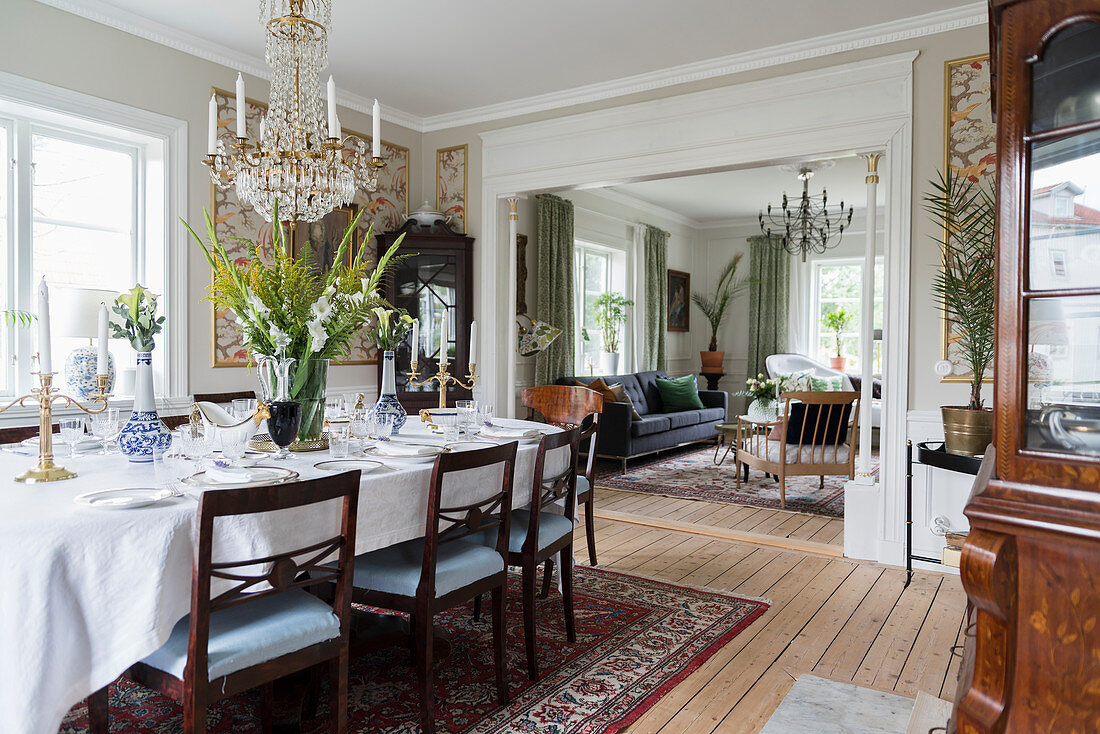 Set dining table in classic dining room with open doorway leading into living room