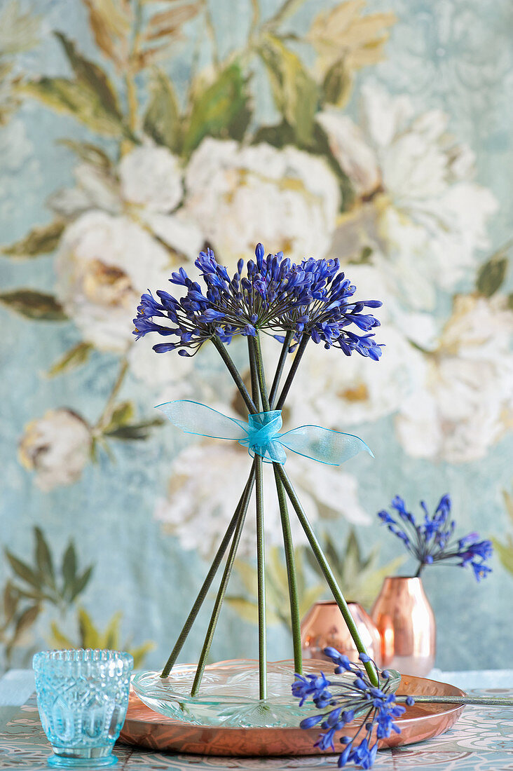 Standing arrangement of blue agapanthus on copper tray