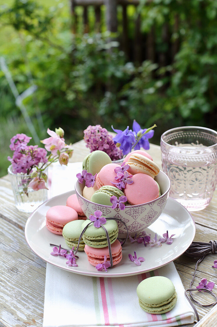 Lilacs and aquilegia in small glasses and macarons decorated with lilac flowers