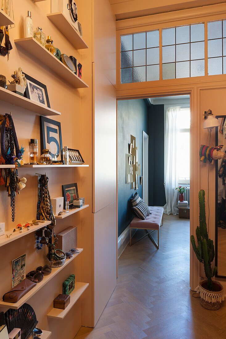 Passageway with white shelves, decorative items and a view into a blue room