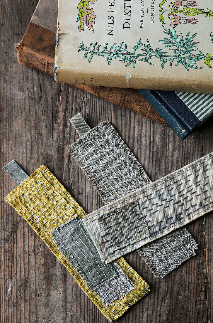 Embroidered bookmarks on old wooden table with vintage books