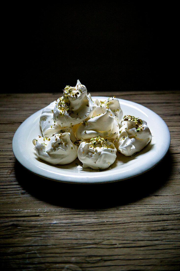 Plate of white merengues with pistachios