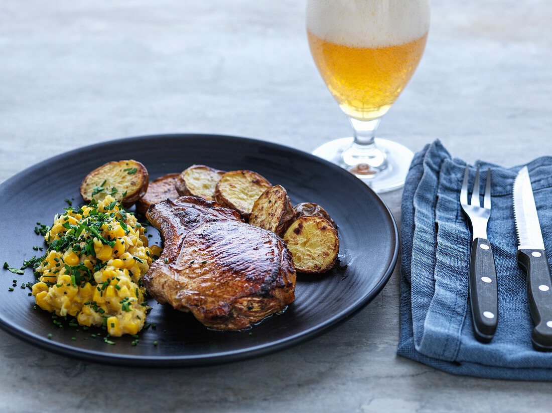 Gebratenes Schweinekotelett mit Mais und Bratkartoffeln