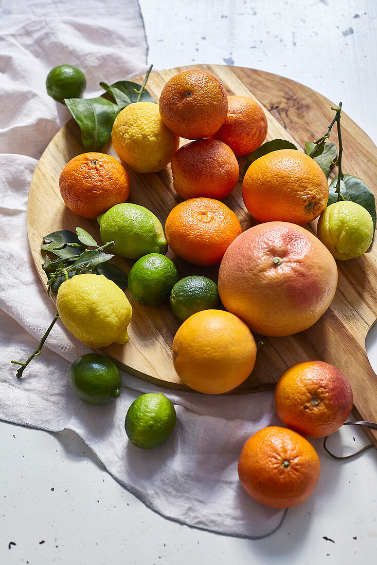 Various citrus fruits on a round wooden cutting board