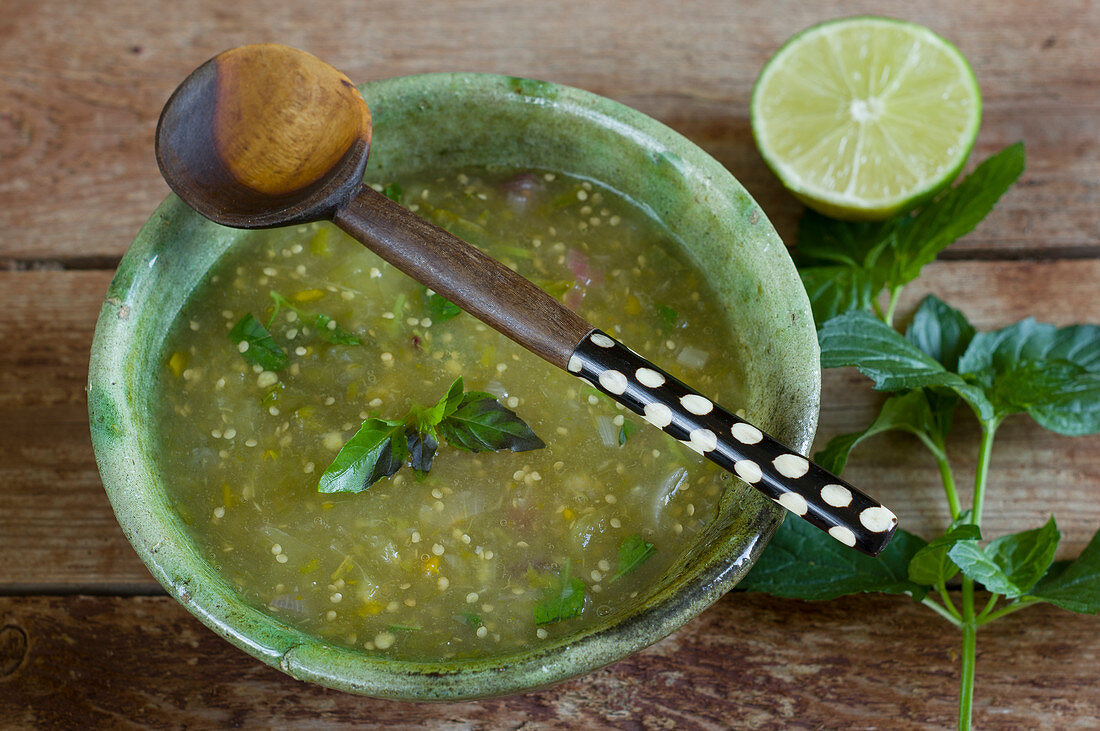 Salsa Verde in a green ceramic bowl with a wooden spoon