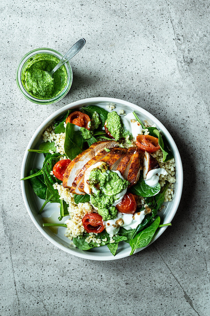 Fitness bowl with chicken breast, bulgur, spinach and pesto