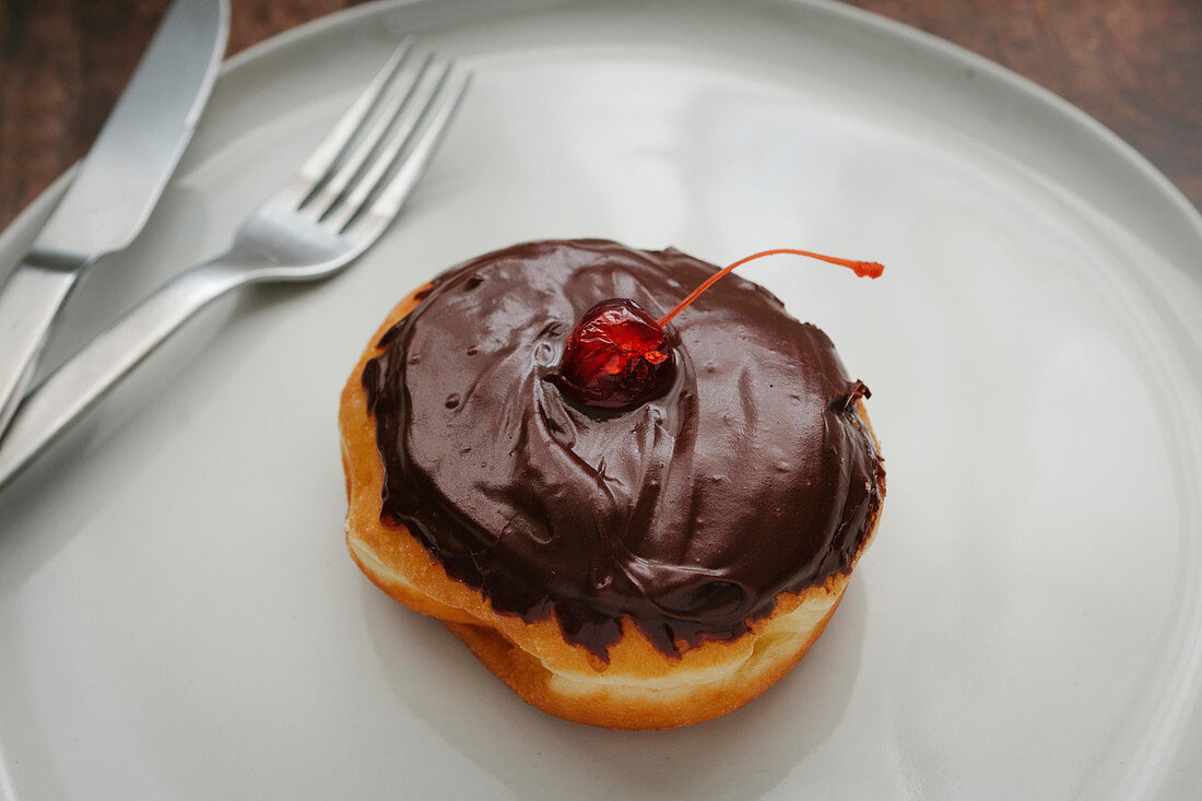 Boston Cream Donut mit Schokoglasur und Belegkirsche