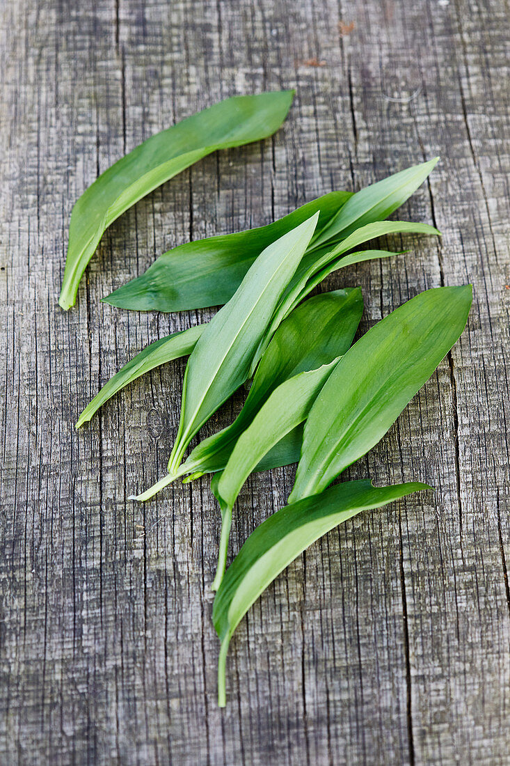 Several wild garlic leaves on a wooden surface