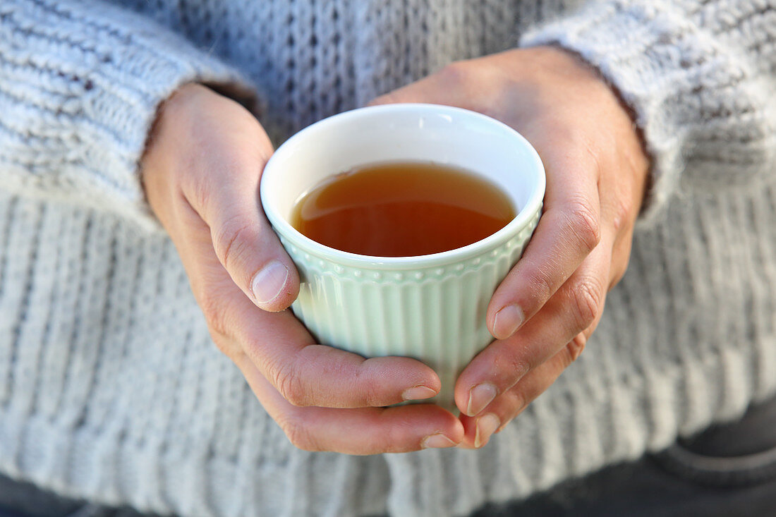 Hände halten Teetasse