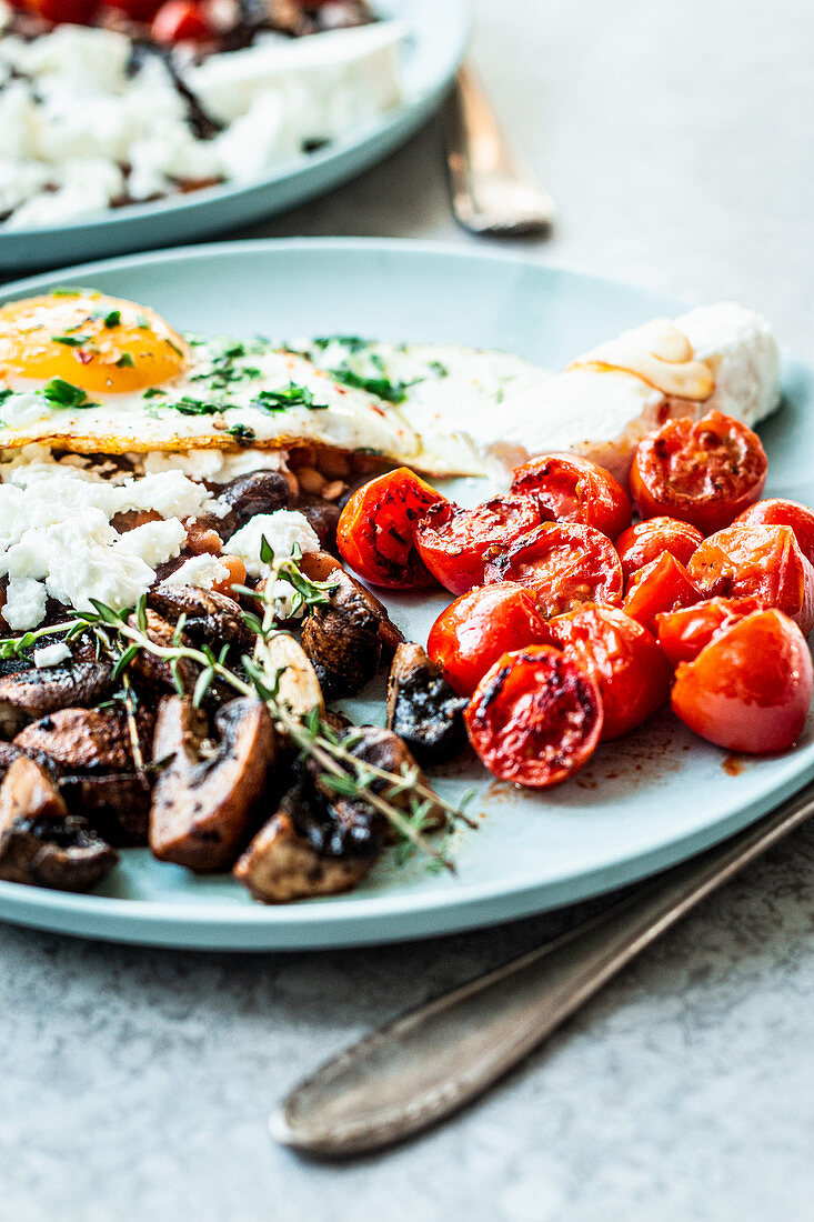 Vegetarisches englisches Frühstück mit Spiegelei, Pilzen, Tomaten und Feta