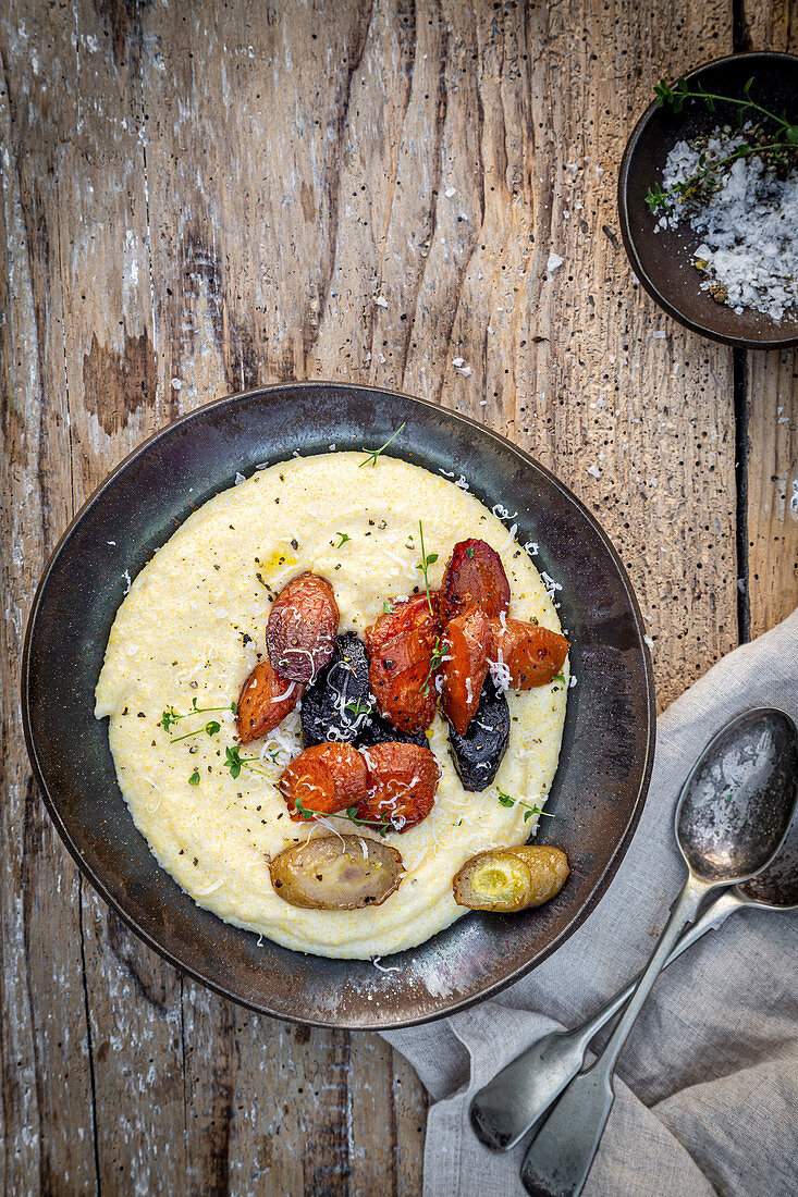 Vegan creamy polenta with roasted musgrooms, on a wooden background.