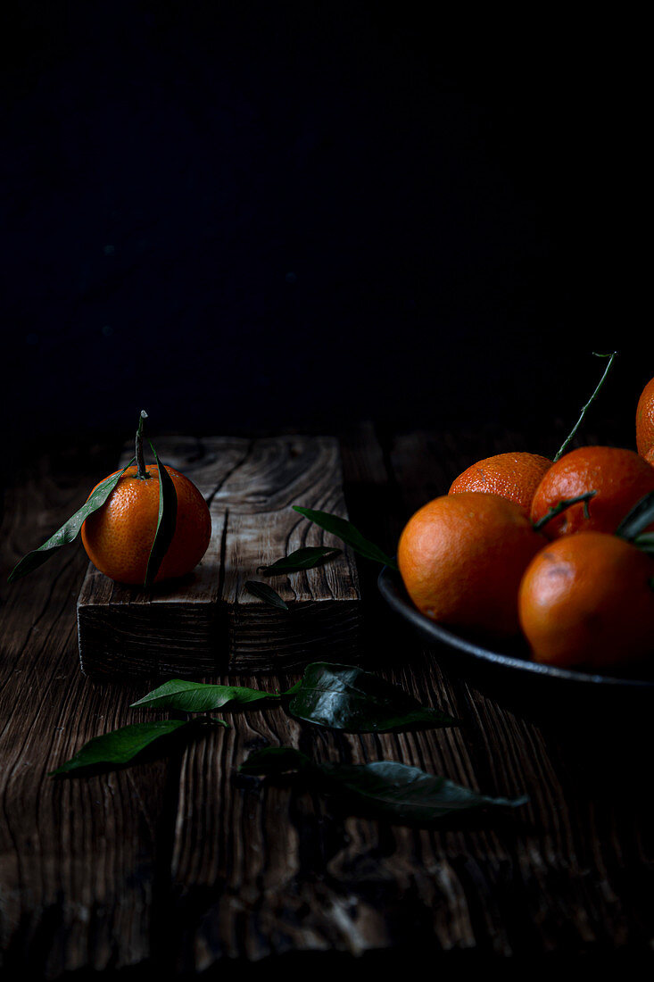 Clementines with leaves on wood. Moody photography
