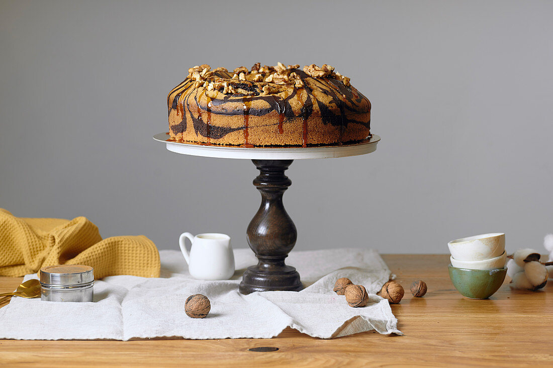 Vegan marble cake with walnuts on wooden cake stand