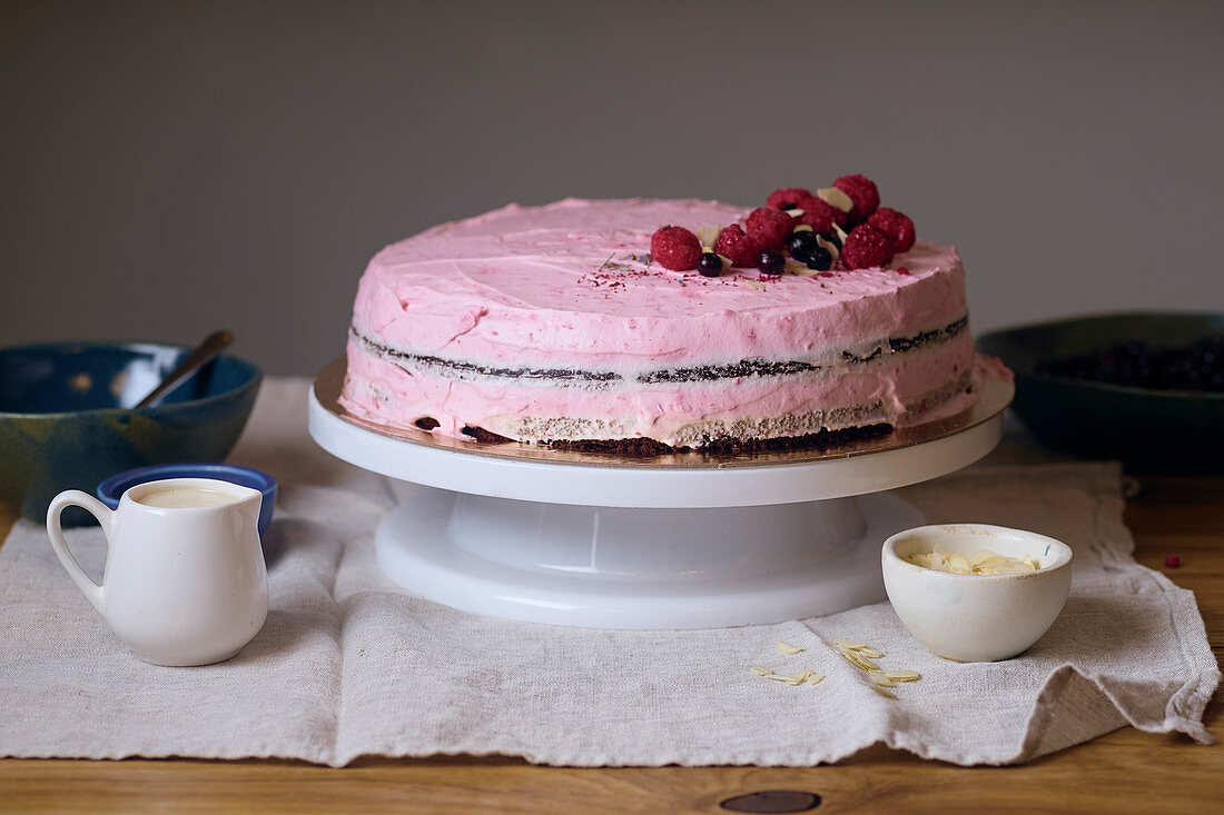 Vegan tart with raspberries and chocolate on white cake stand