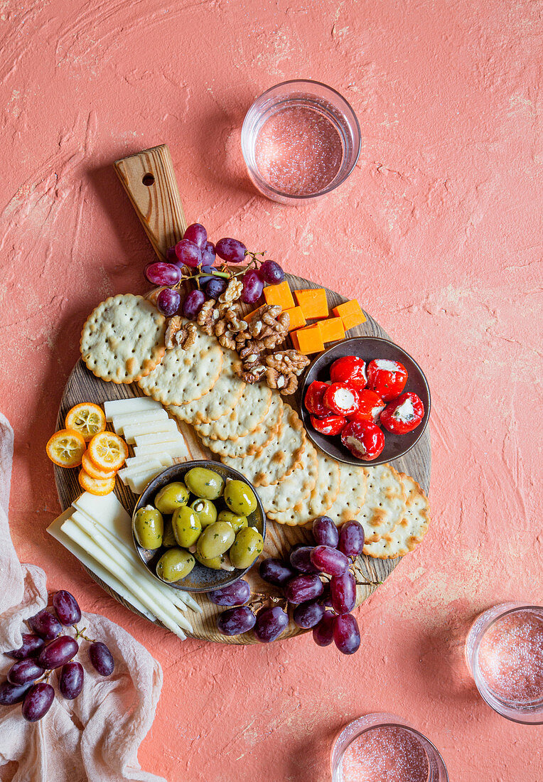 Käsebrett mit Crackern, Trauben, Oliven, gefüllten Minipaprika und Walnüssen