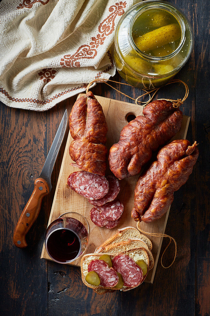 Several hard sausages with pickles and red wine