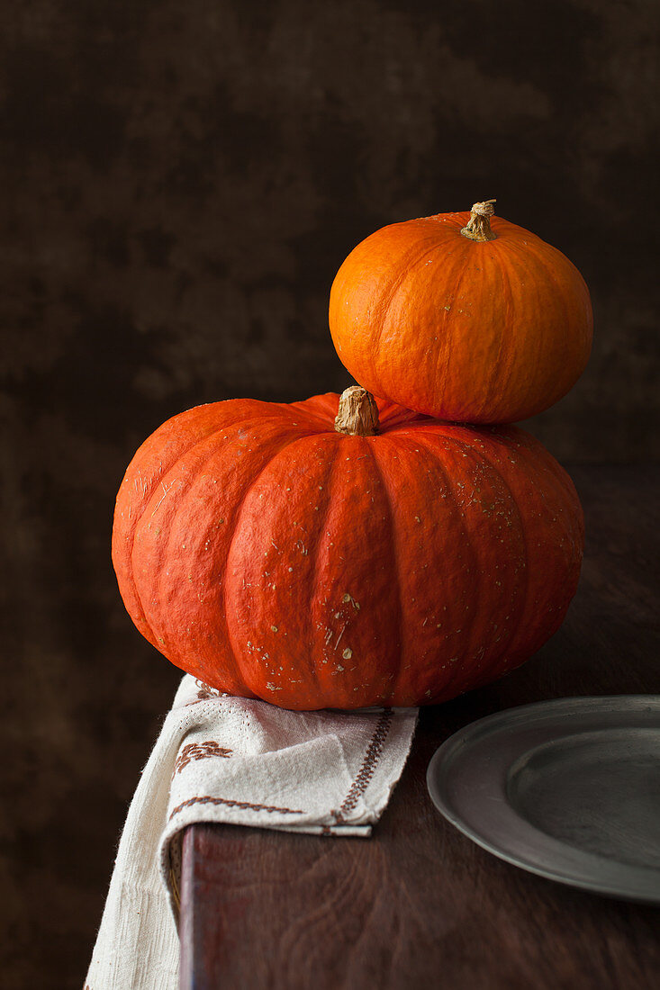 Two orange pumpkins on a rustic wooden table