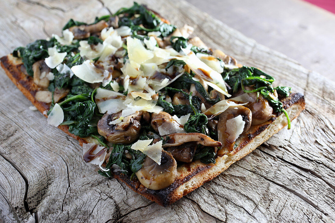 Spinach mushroom flatbread pizza with shaved parmesan cheese