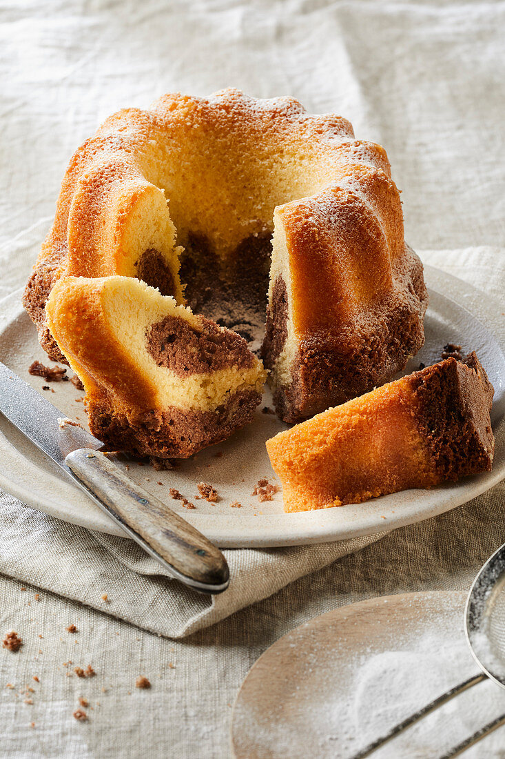 Marble cake with icing sugar, partly sliced