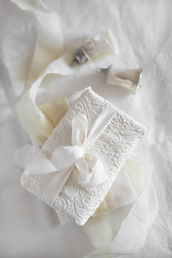 Gift wrapped in patterned white fabric and tied with fabric ribbon
