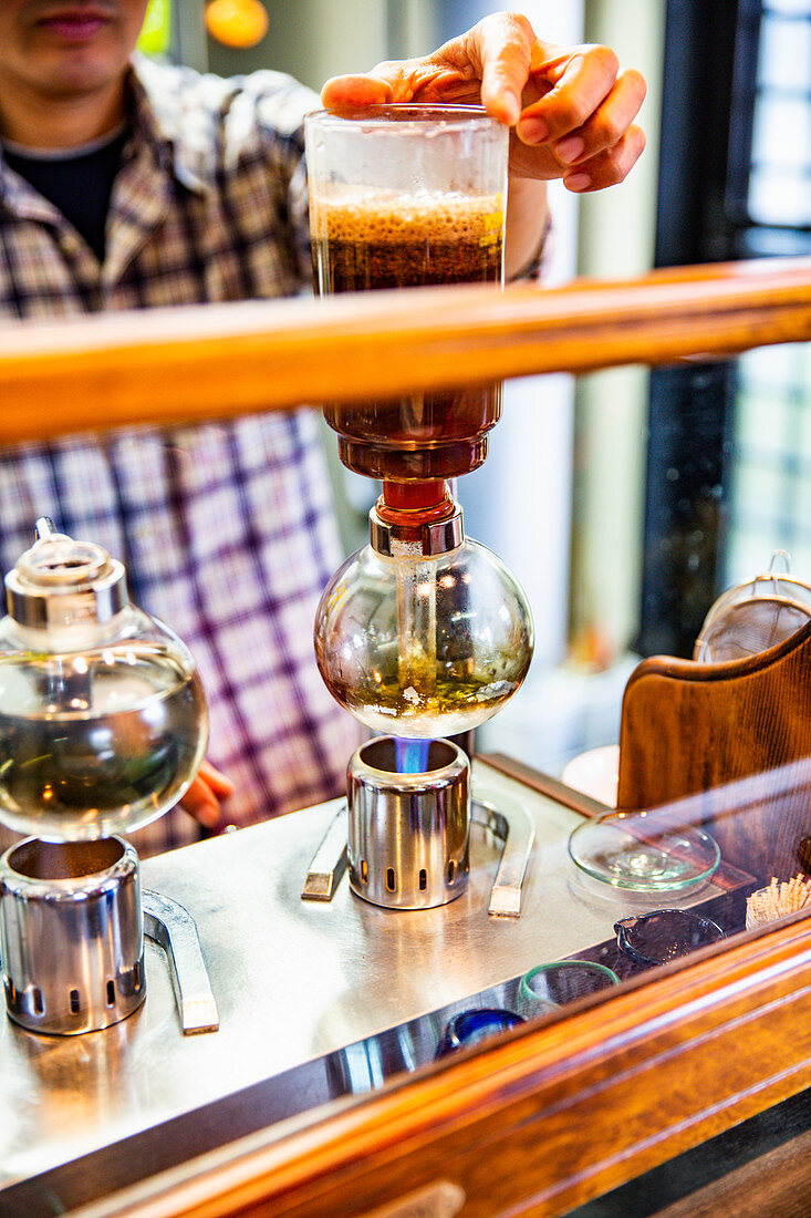 Mann bereitet Kaffee mit japanischer Kaffeemaschine vor