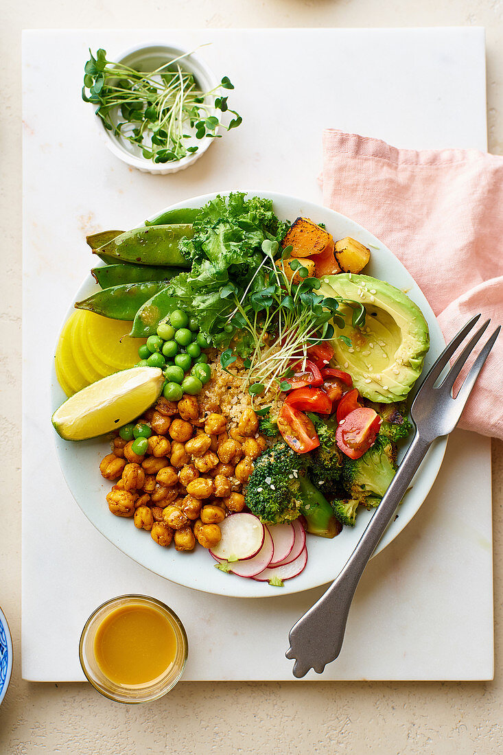 Healthy vegetarian lunch bowl with avocado, chickpeas, quinoa, microgreens and vegetables