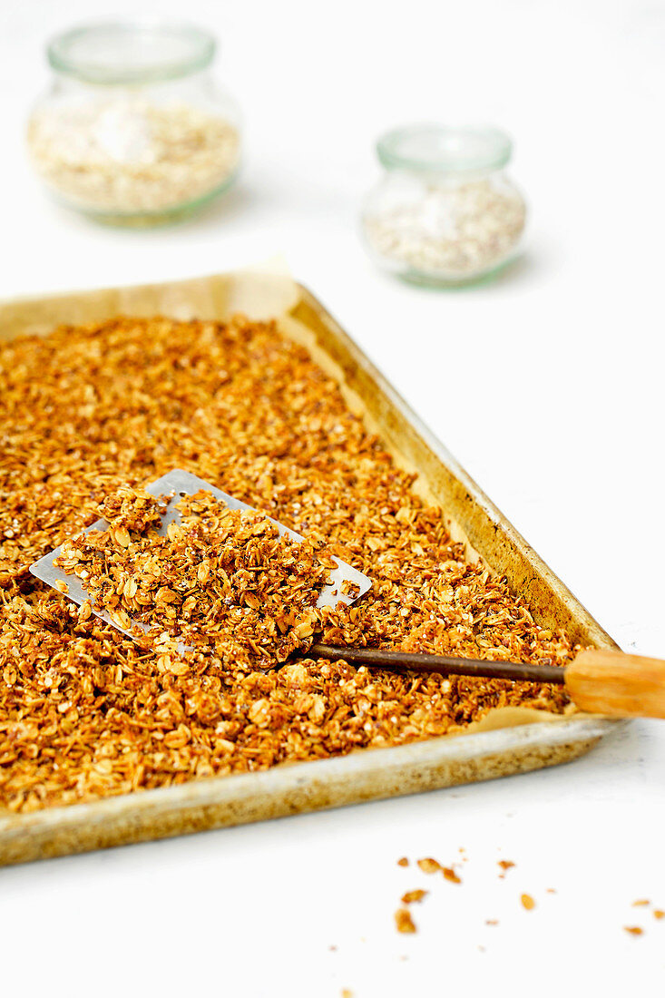 Selbstgemachtes Granola-Müsli aus Haferflocken und Quinoa auf Backblech