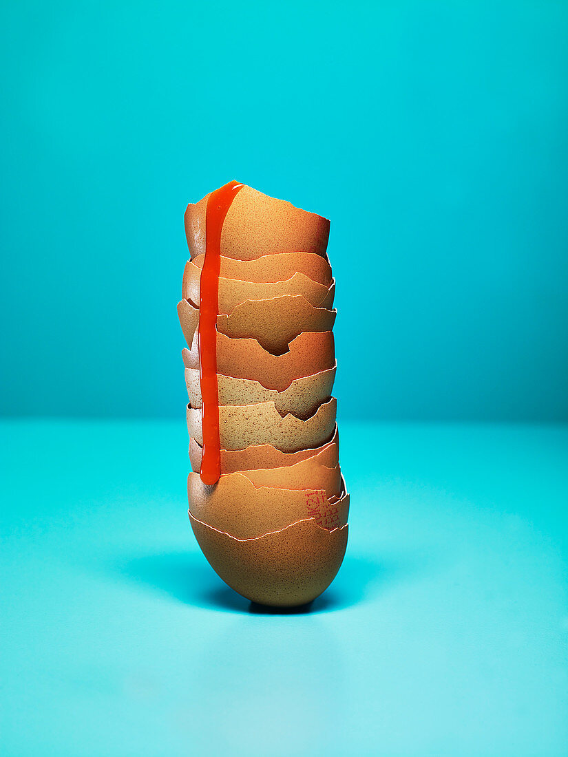 Hen egg shells against a blue background. Sauce dripping down stacked shells.