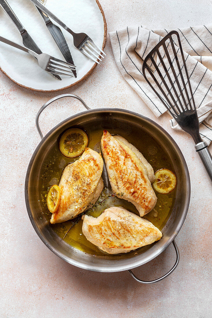 Baked chicken breast with lemon and thyme on the pan.