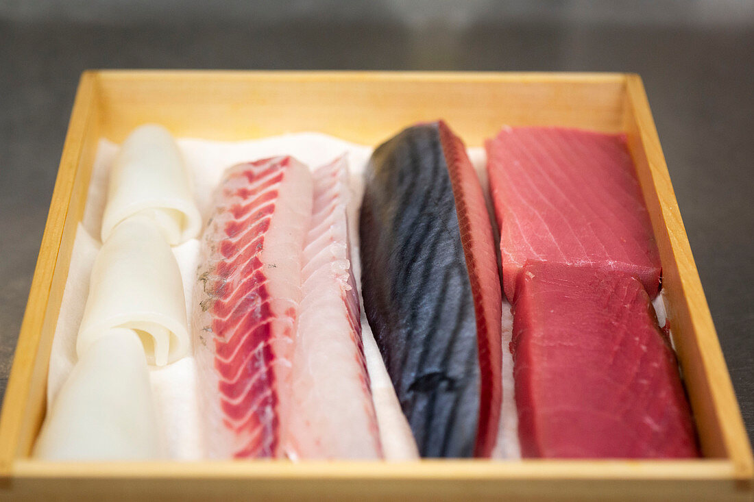 Verschiedene Fische für Sushi-Zubereitung in Holzkistchen