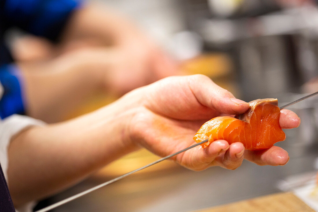 A piece of raw salmon being skewered