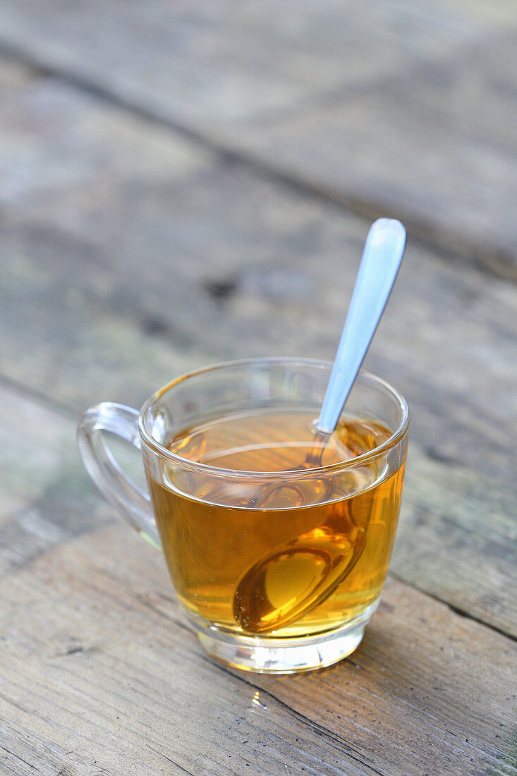 Herb tea in a glass cup with a spoon