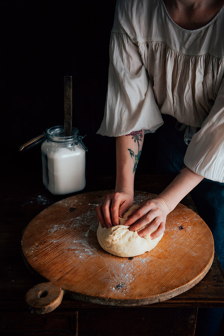 Woman kneads yeast dough for challah bread on a wooden board