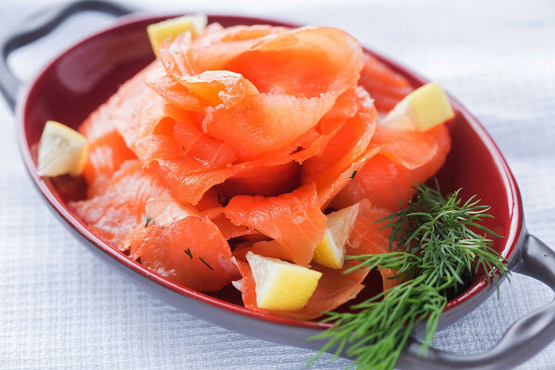 Slices of fresh salmon with pieces of lemon and aromatic dill placed on plate