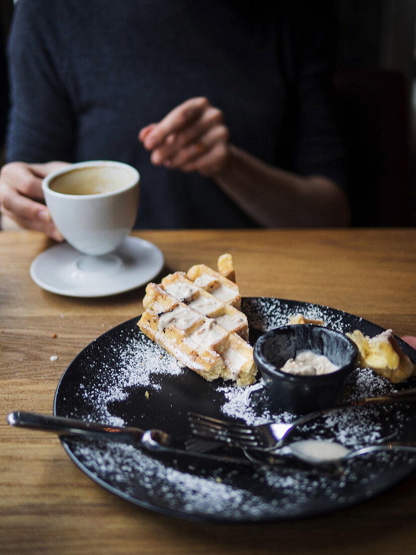 Reste von Waffeln mit Puderzucker und Eiscreme, dazu Kaffee