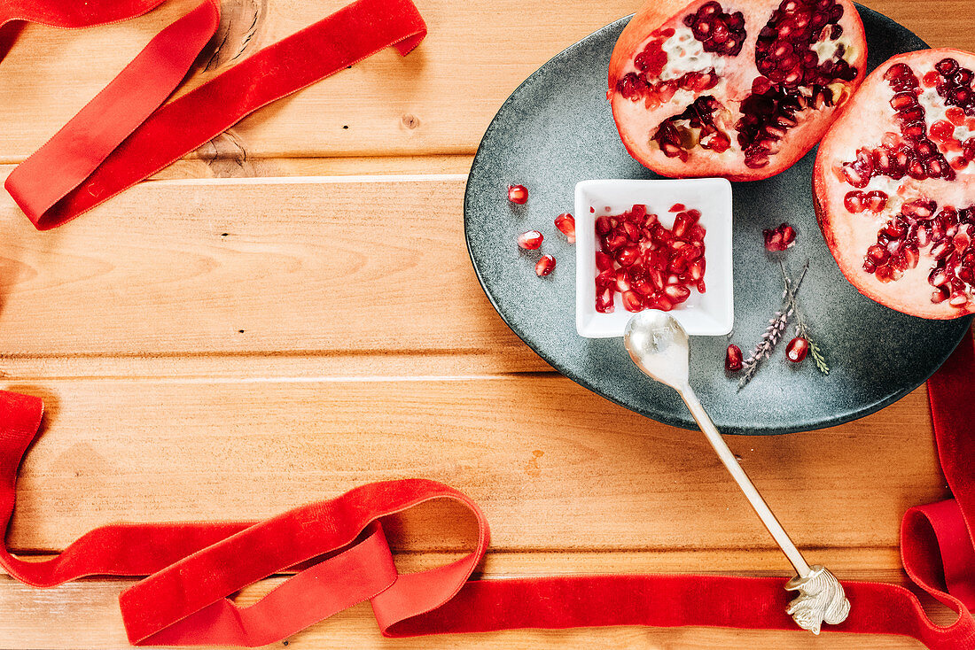 Stilleben mit Granatapfel und leuchtend rotem Samtband