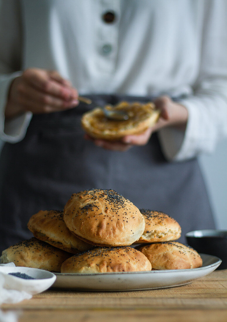 Plate with fresh poppy seed buns placed on lumber table