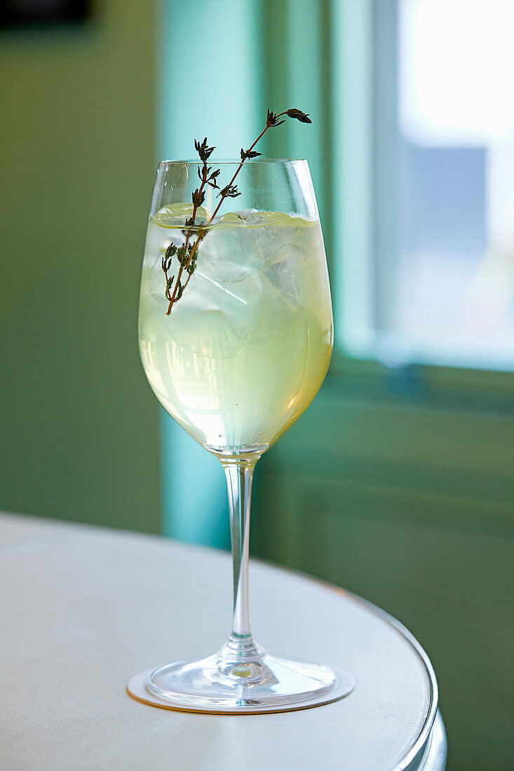 Limoncello spritz with thyme and ice cubes