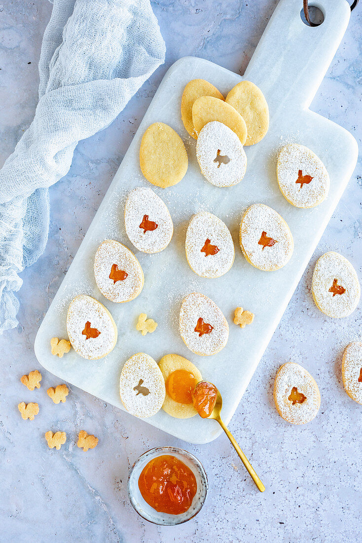 Easter egg cookies with apricot jam on a marble cutting board