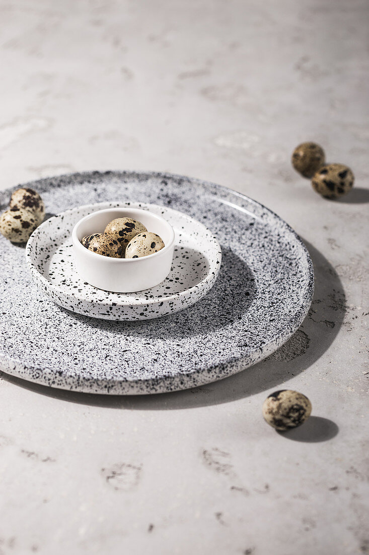 Quail's eggs in a bowl on speckled plates