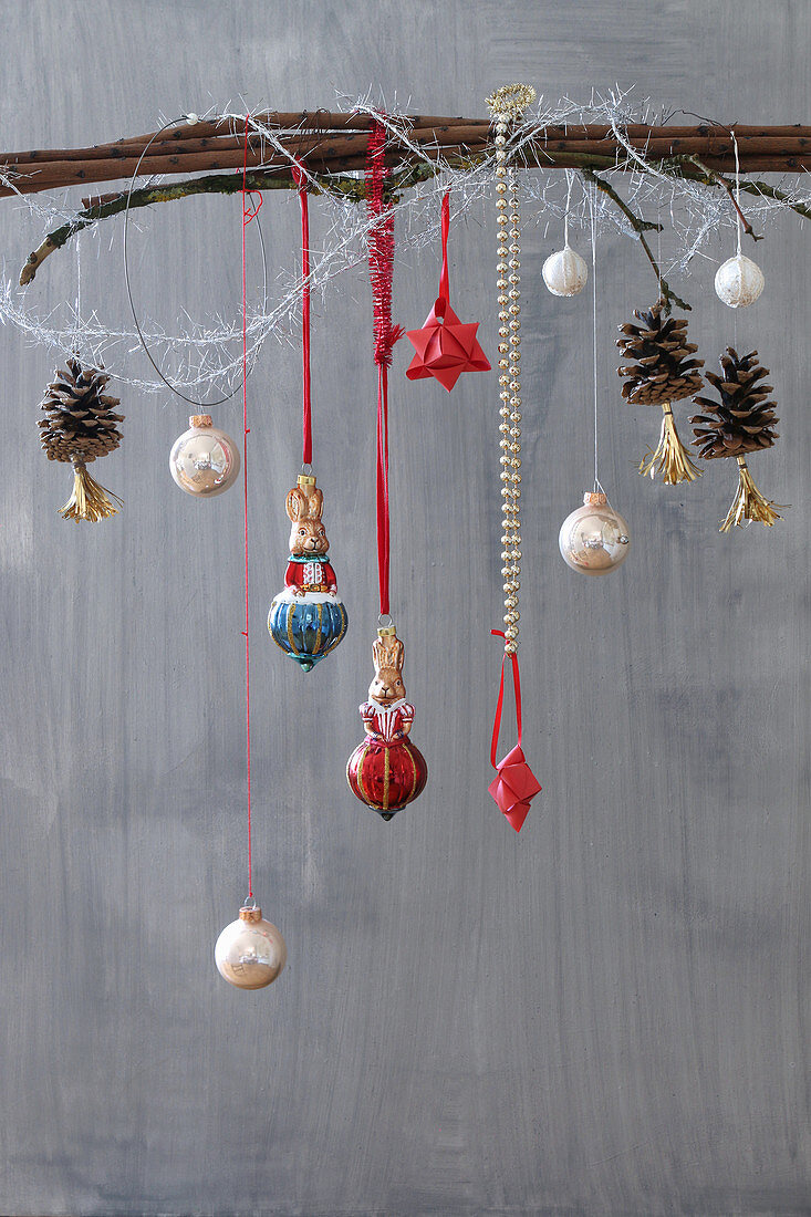 Branch adorned with Christmas-tree decorations and pine cones with tassels