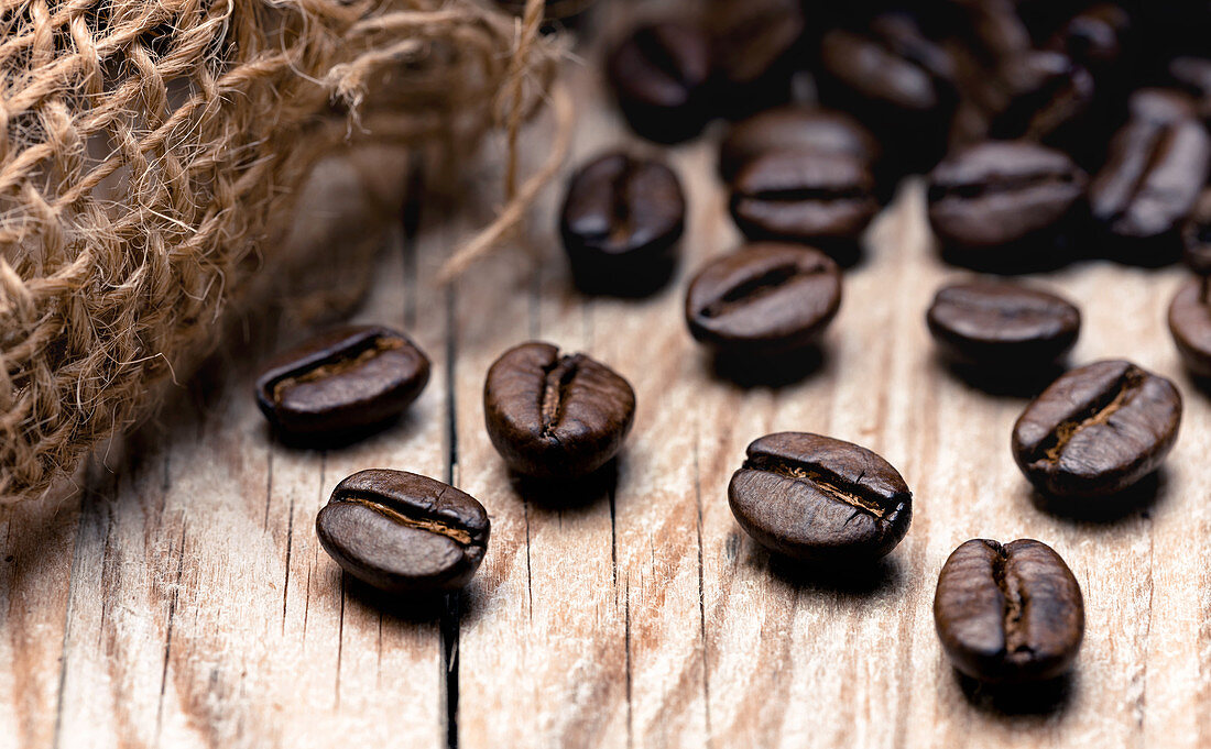 Geröstete Kaffeebohnen auf Holzuntergrund (Nahaufnahme)
