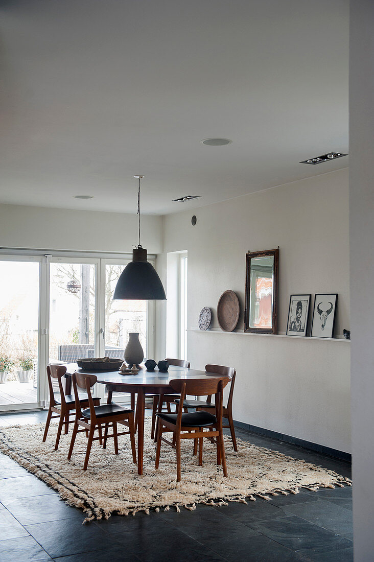 Dark chairs around oval table in dining room with stone-flagged floor