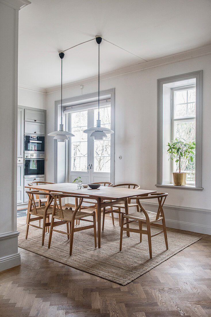 Designer chairs around dining table in front of open-plan kitchen in period building