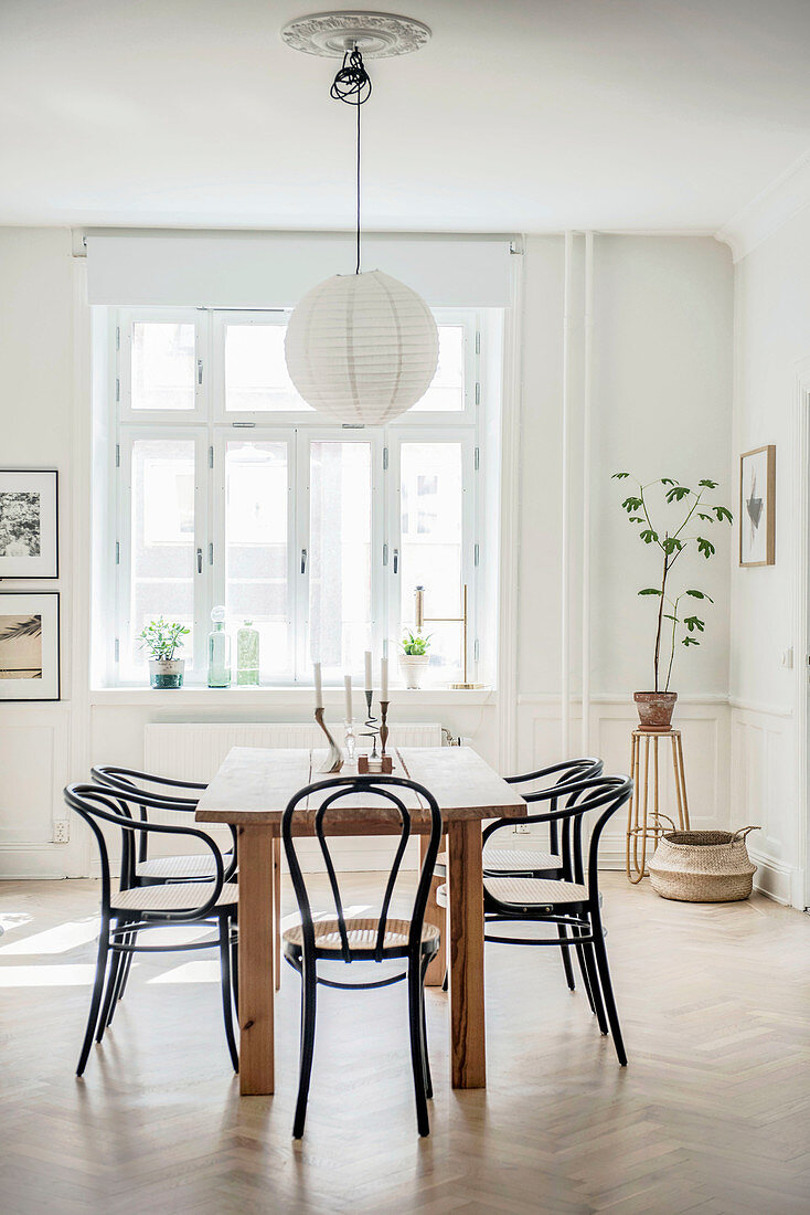 Schwarze Kaffeehausstühle am Esstisch im Altbau mit Kassettenwand