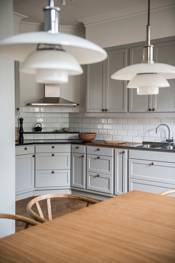 Dining table in front of classic kitchen with pale grey panelled fronts