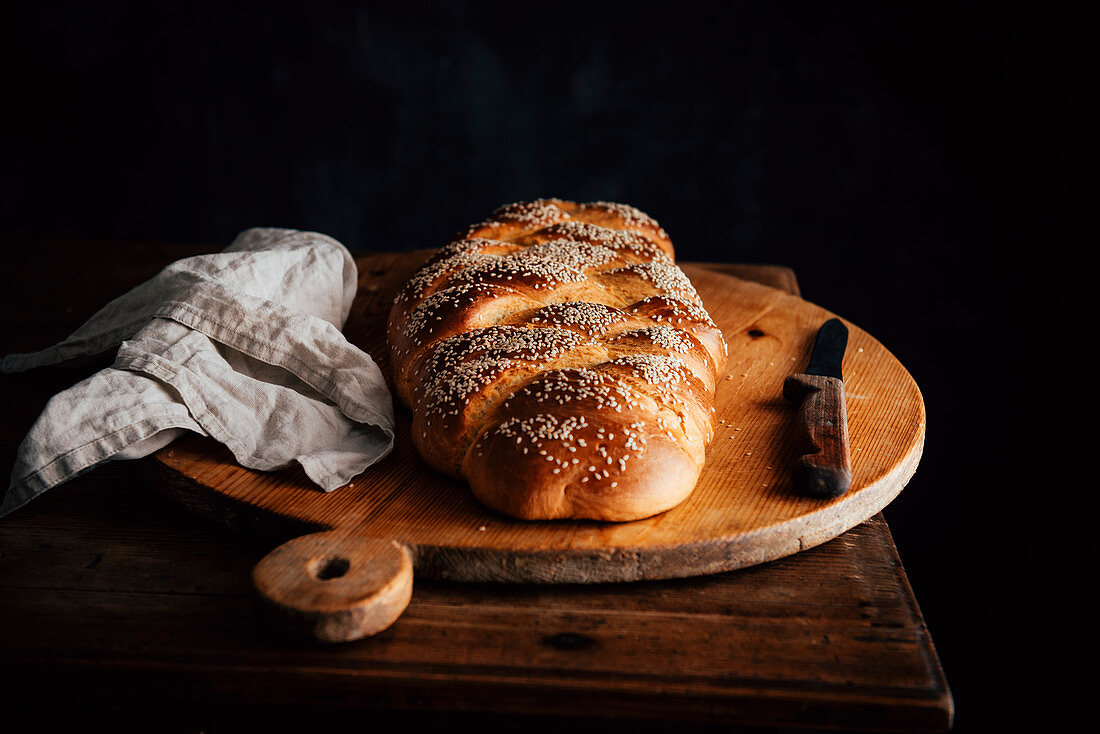 Challah bread with sesame seeds on a rustic wooden board